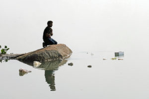 <p>A man prays on a rock in the polluted Brahmaputra River in Tezpur, Assam, India (Image: Friedrich Stark / Alamy)</p>
