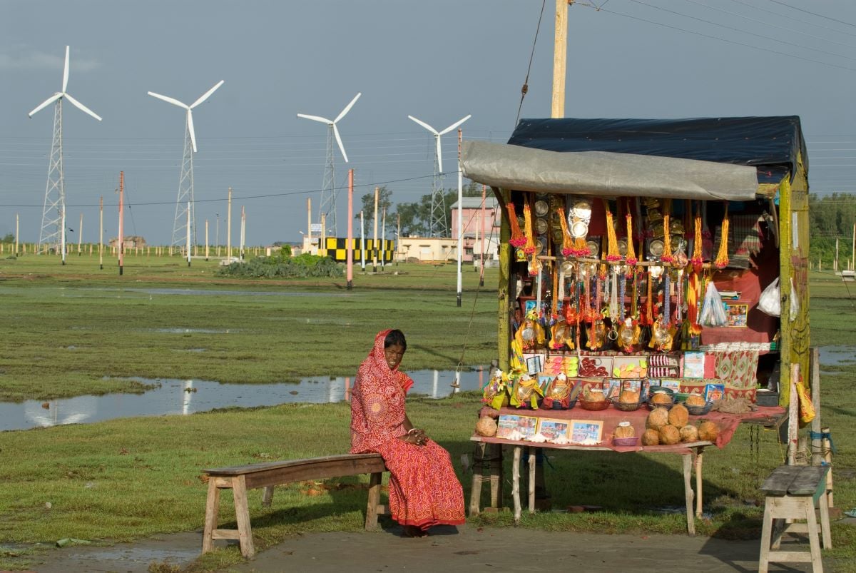 A woman selling devotional toys with windmills to her backin front of a wind farm