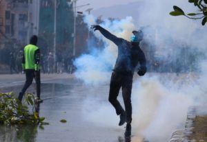 <p>A man throws a tear gas canister back at riot police during a protest against the US Millennium Challenge Corporation grant in Kathmandu, Nepal, on 24 February 2022. Protests broke out over the grant at the end of February over concerns it will violate Nepali sovereignty. (Image: Aryan Dhimal / Alamy)</p>