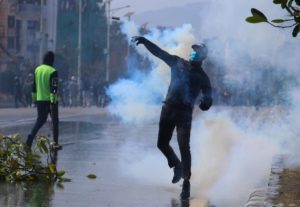 A man throws a tear gas canister back at riot police during a protest against the US Millennium Challenge Corporation grant in Kathmandu, Nepal