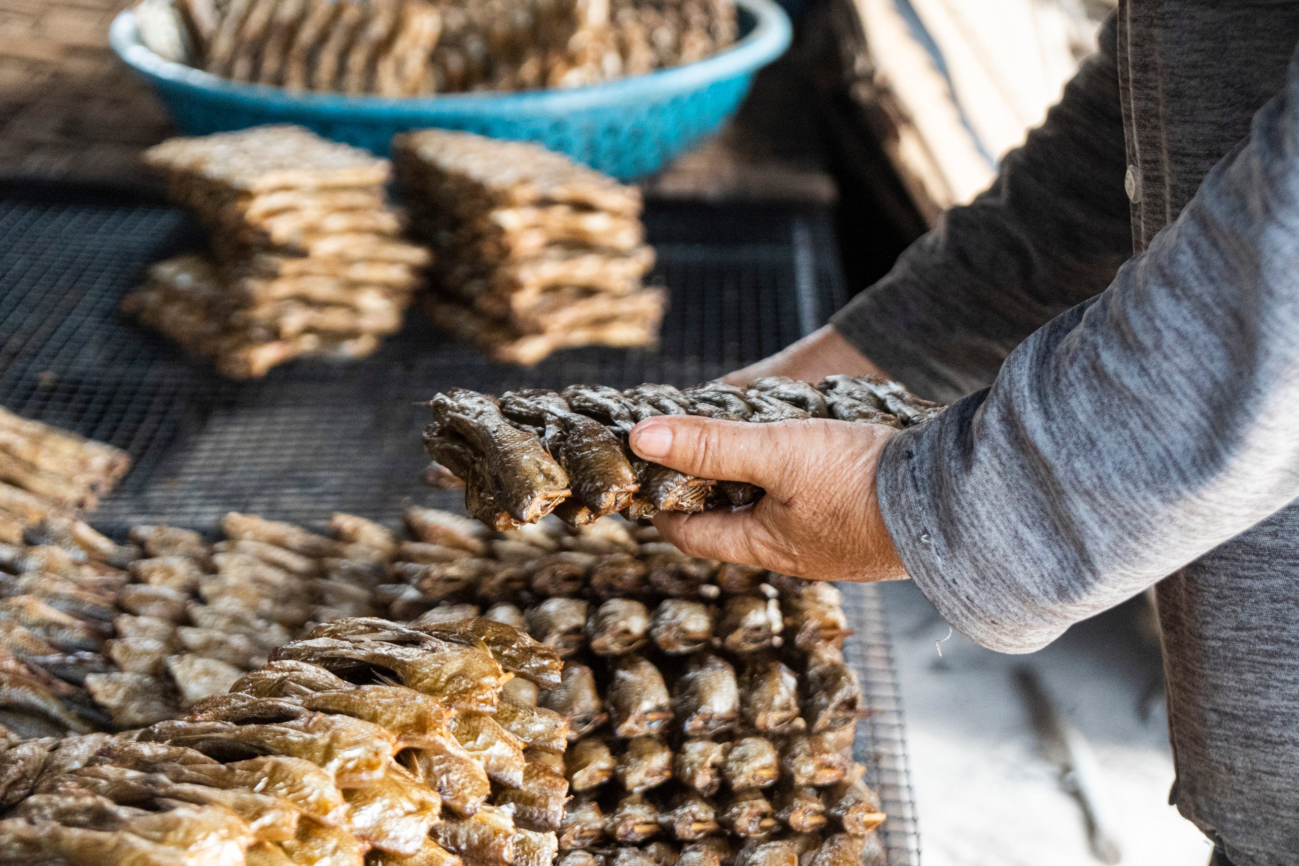 person handling bundles of dried fish