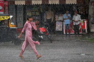 A woman dressed in pink walks in the monsoon rain in Jammu