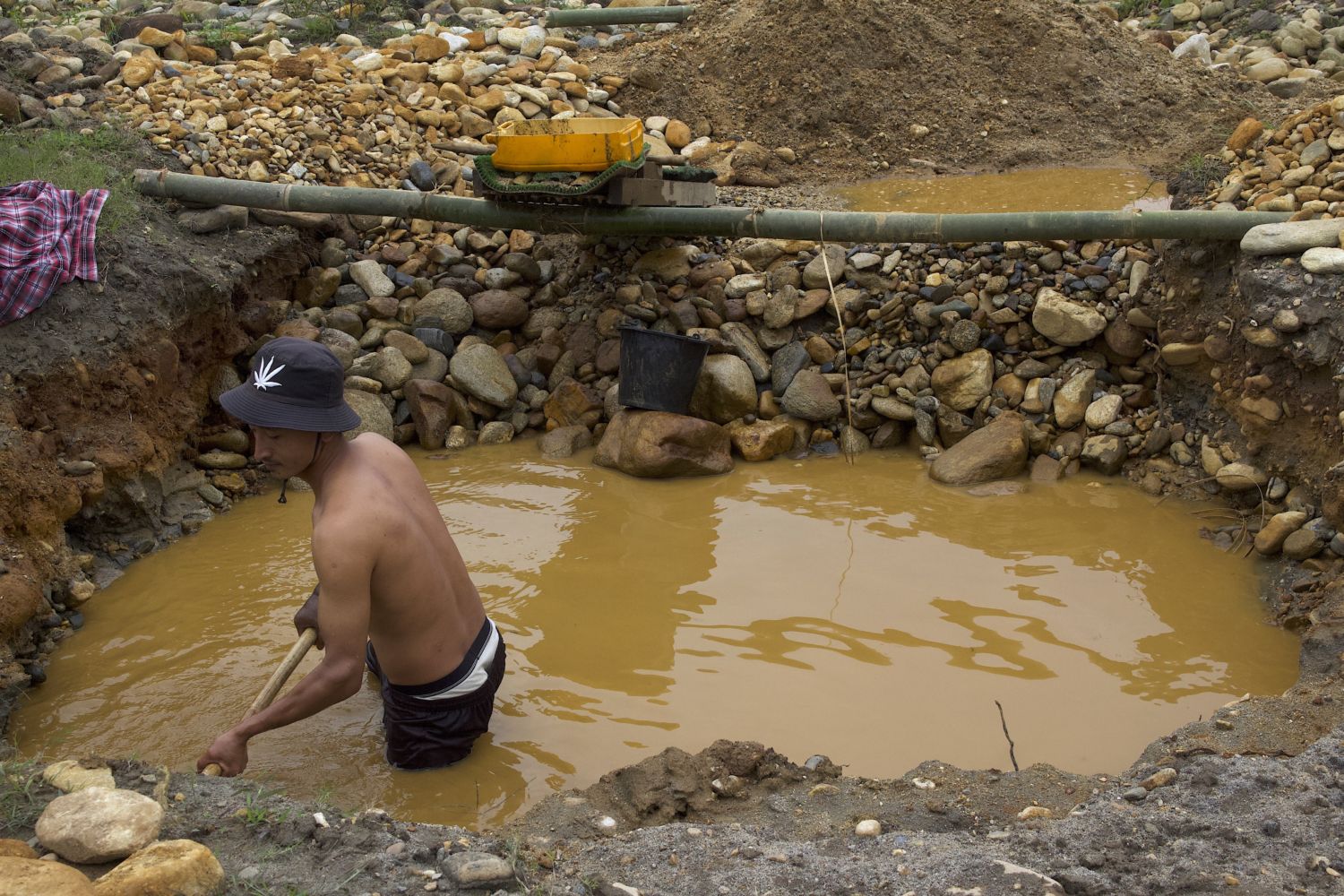 A miner digs a trench to pan for gold near the Mali River