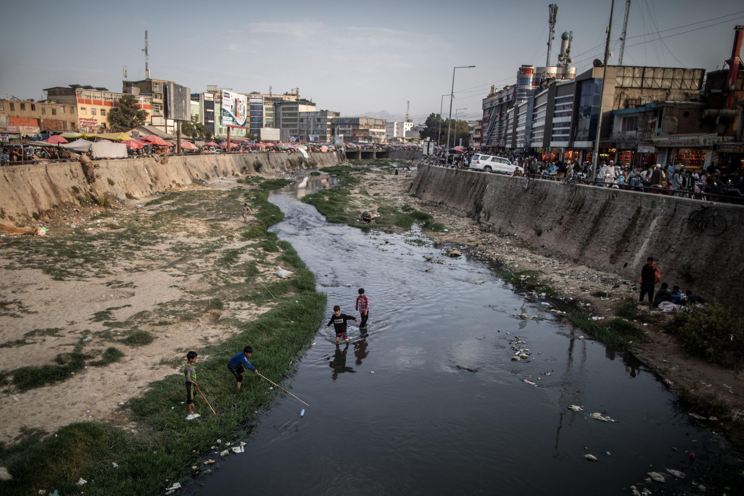<p>Boys race to fish a plastic bottle out of the heavily polluted and littered Kabul River in Kabul, Afghanistan, in September 2021. The bottles can be sold on for recycling for small amounts of money. (Image: Oliver Weiken / Alamy)</p>