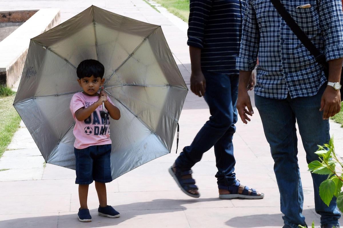 A boy holds an umbrella as a sunshield during a heatwave in New Delhi in April 2022