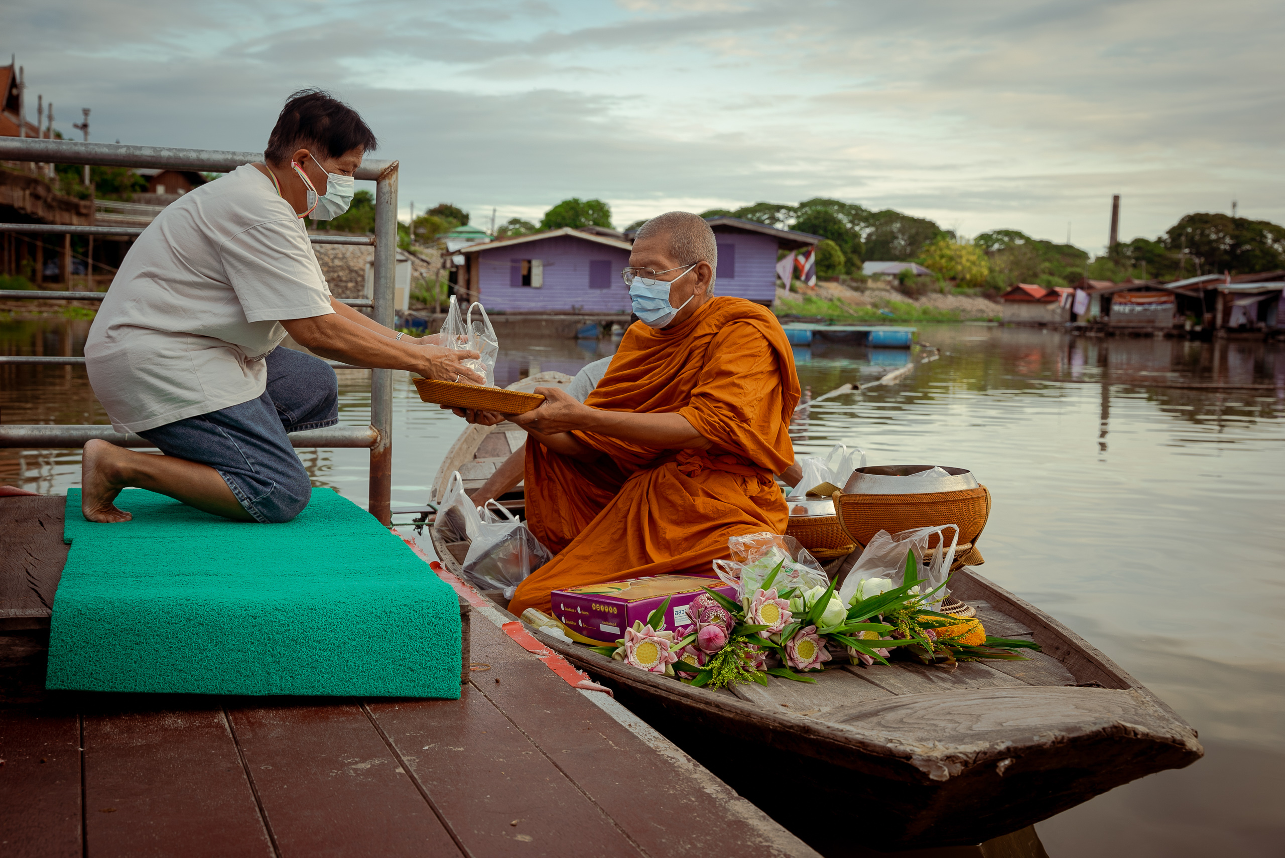 man presenting something to monk on riverboat