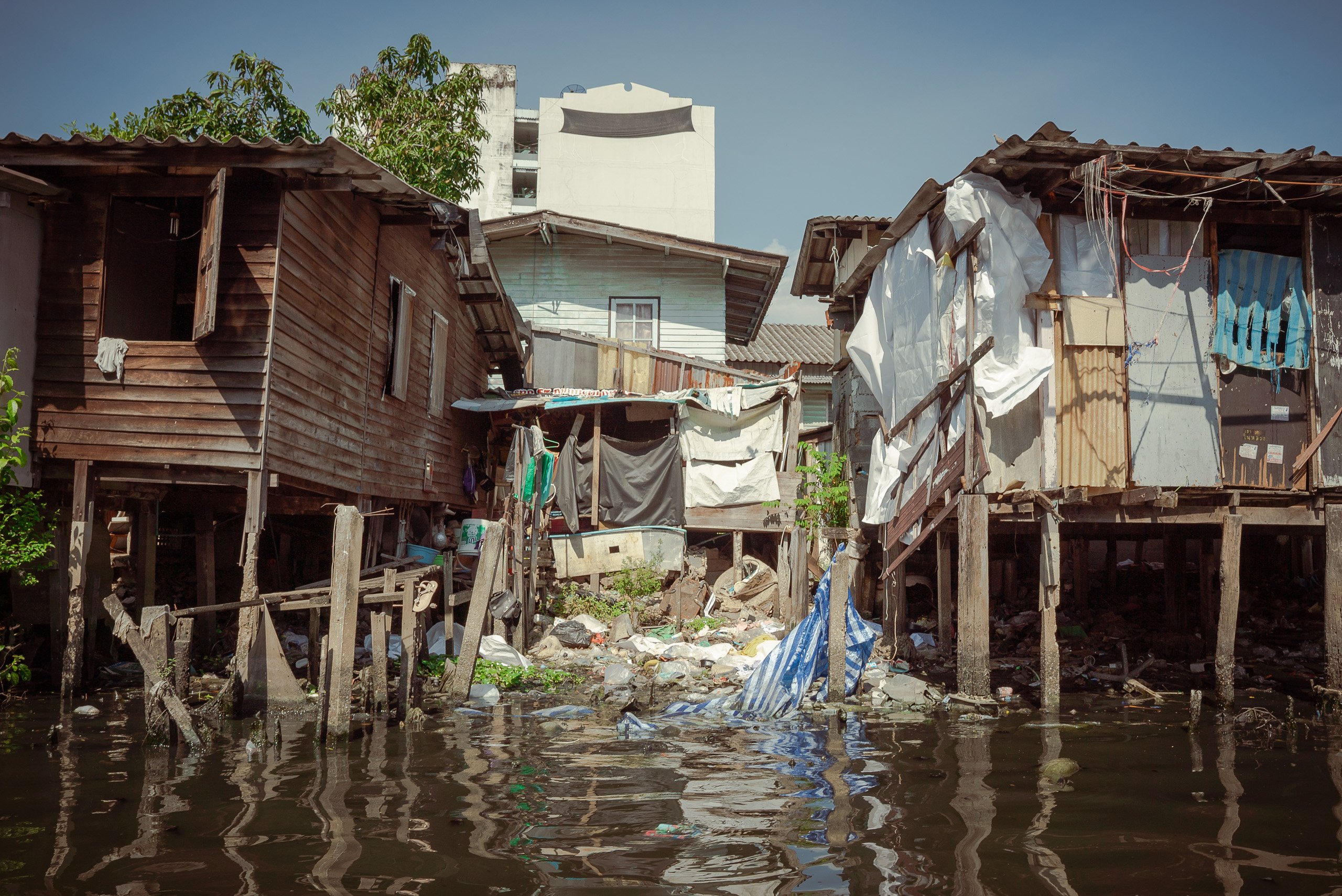 polluted canal between houses on stilts