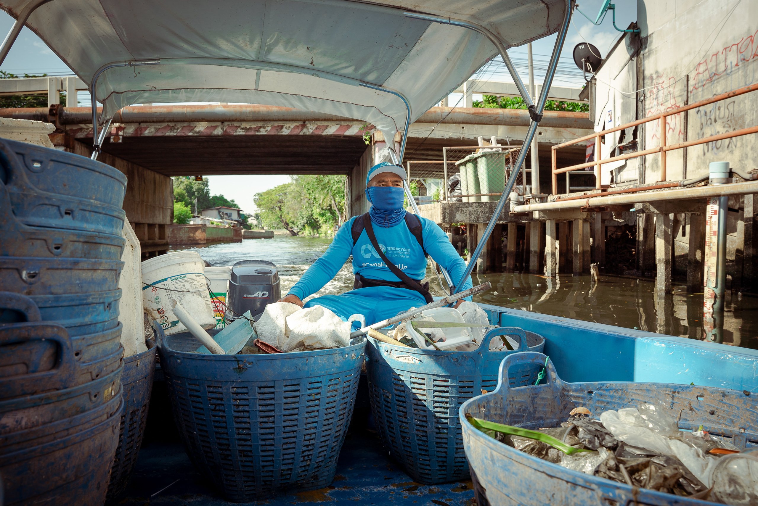 man in boat with baskets of waste