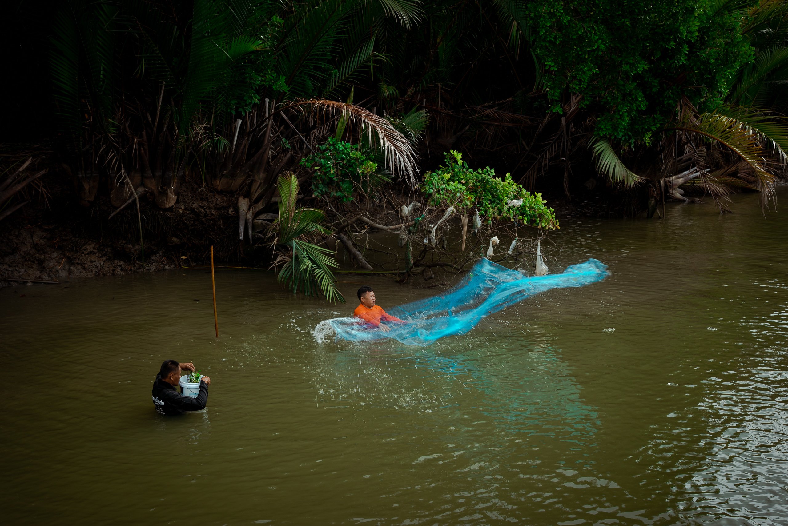 people in muddy water surrounded by large floating plastic