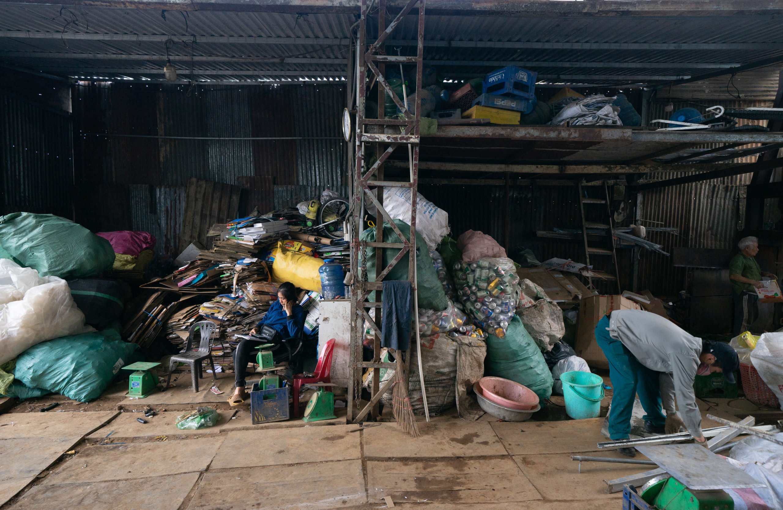 people in warehouse surrounded by bags of plastic waste