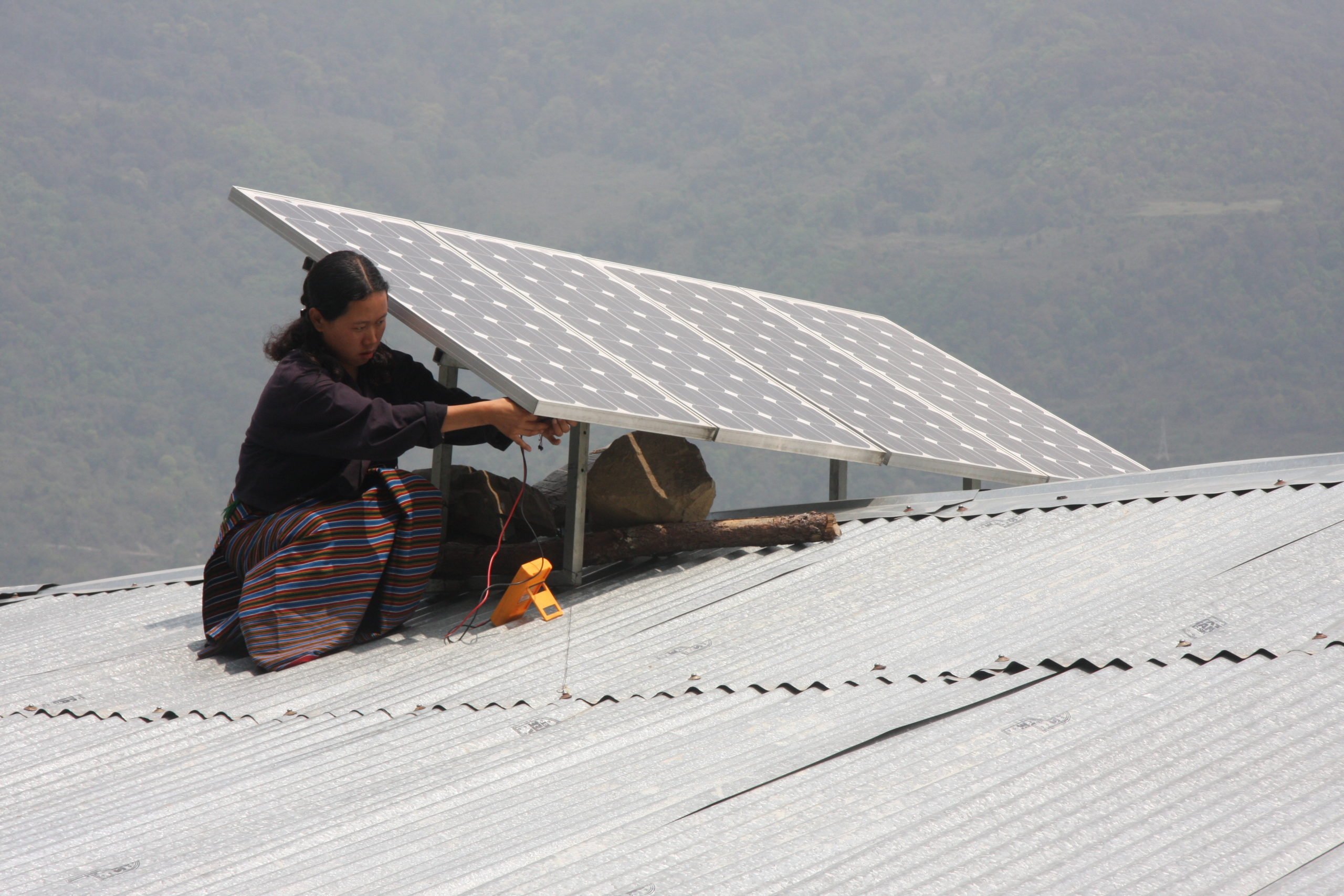 woman on roof holding solar panel, Asian Development Bank