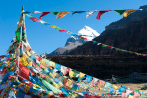 <p>Prayer flags in front of the snow-covered Mount Kailash on the Tibetan Plateau. The mountain is one of the holiest in the world, and climbing it is prohibited. (Image: Alamy)</p>