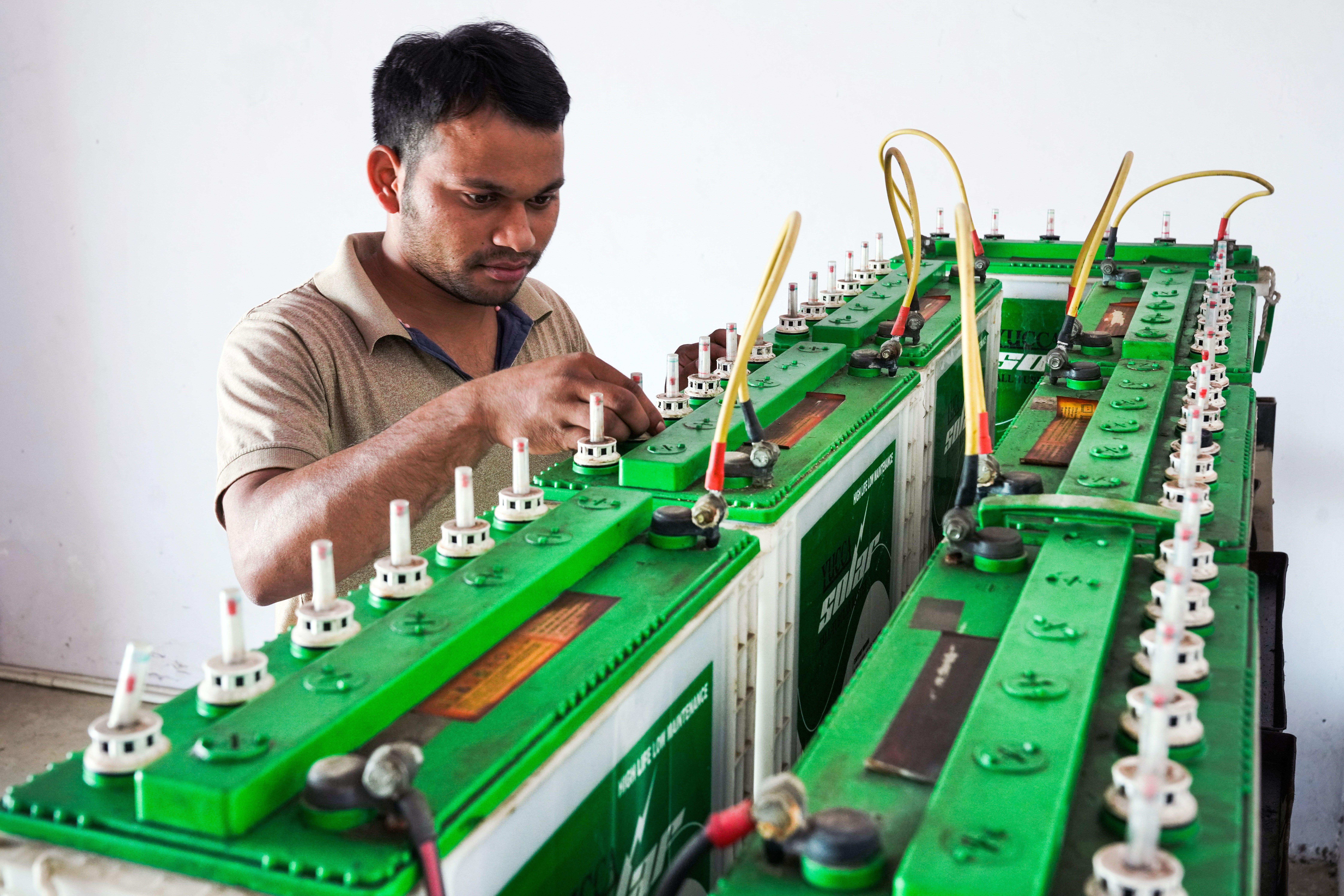 man looking at large batteries for rooftop solar system in India