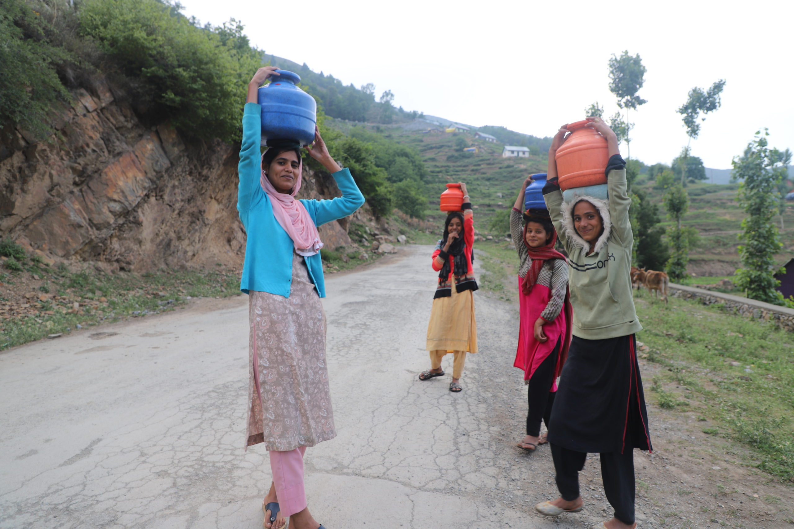 women on street carrying vessels on their heads