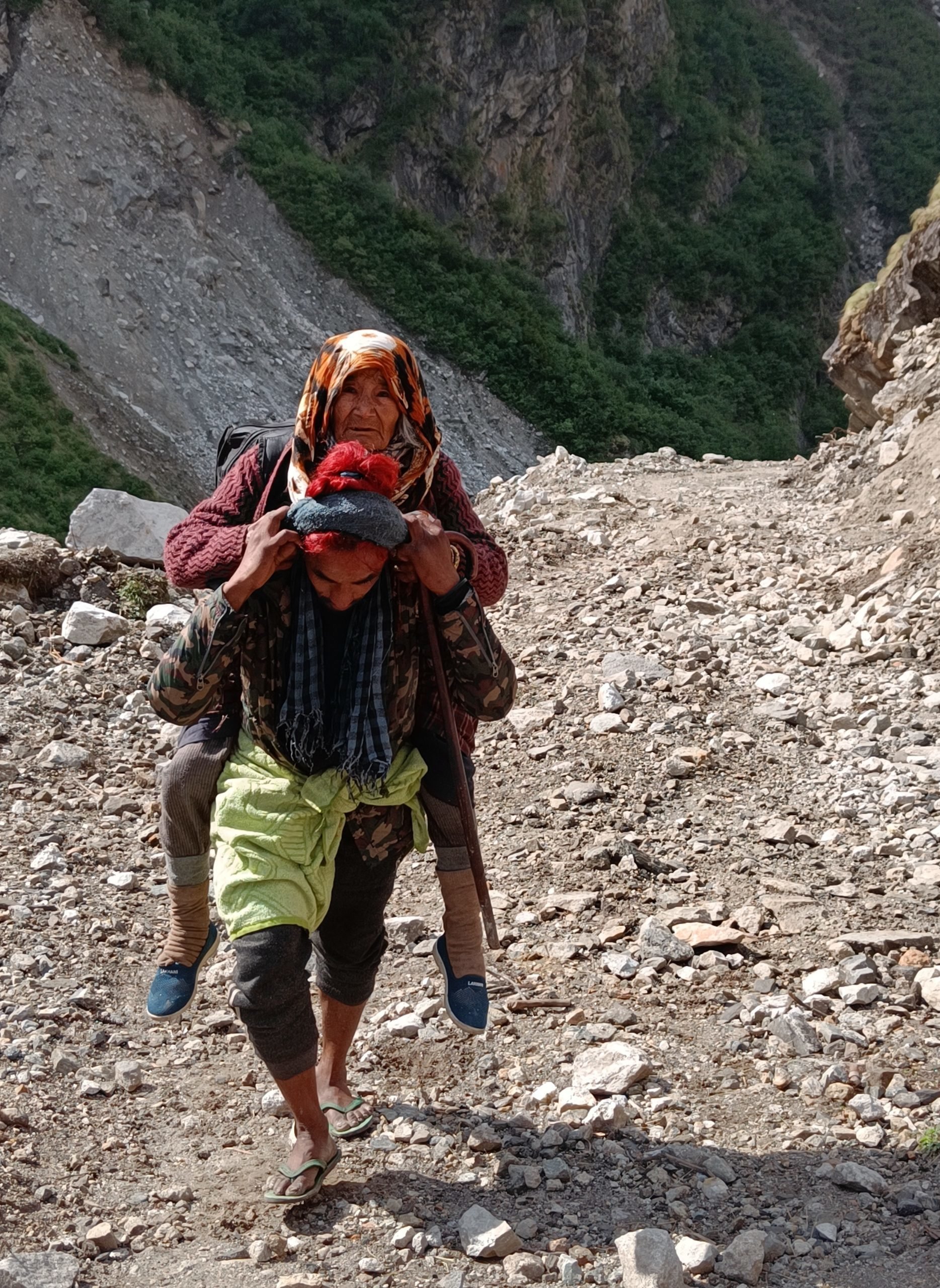 A young man carrying his grandmother to the Johar Valley in May 2022. Elderly members of the Bhutia community make the annual migration for as long as they are able