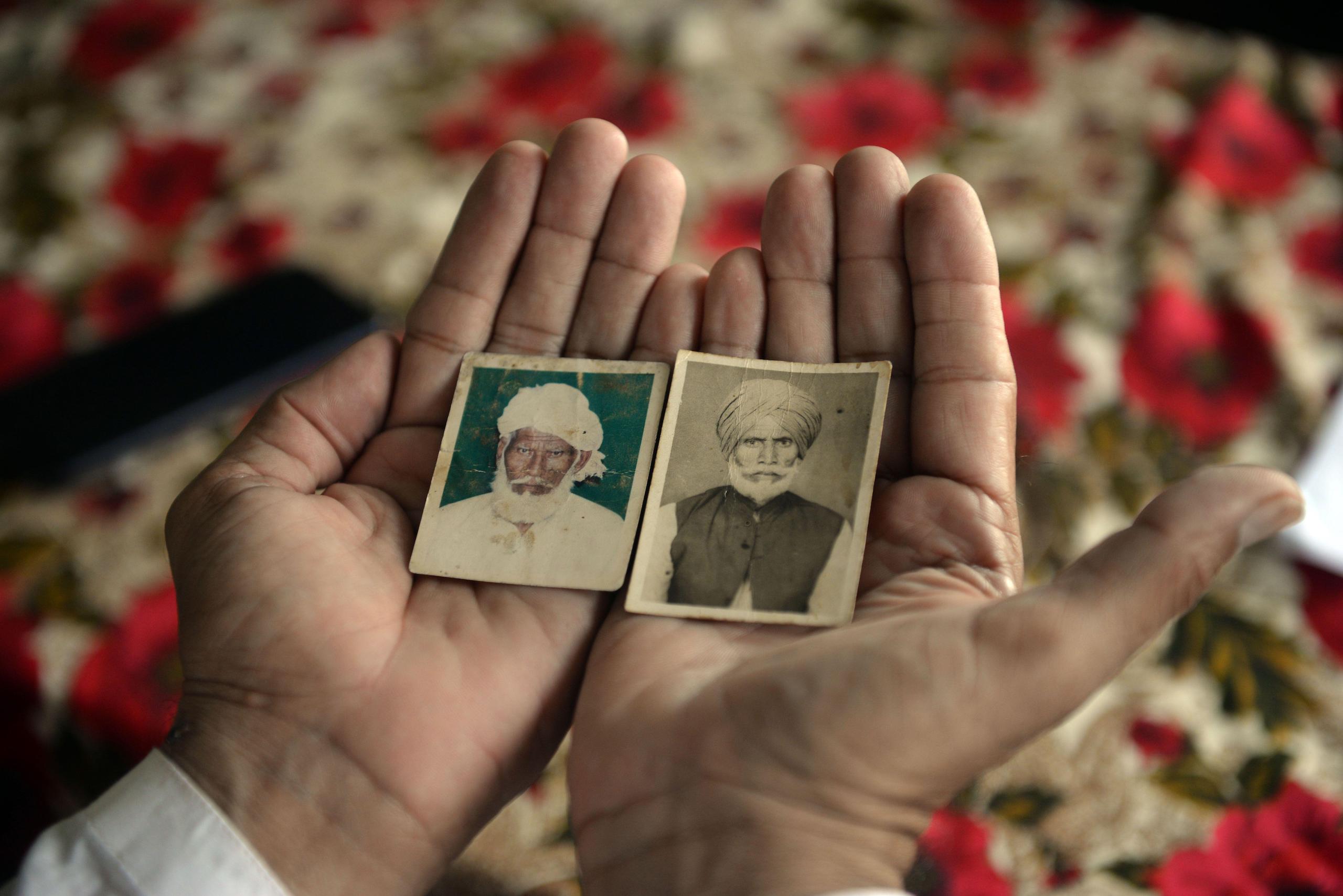<p>Shahbaz Khan shows pictures of his uncle Inayat Khan (left) and his late father Sharif Khan (right), who were separated at the time of Partition (Image: Murtaza Ali / Alamy)</p>