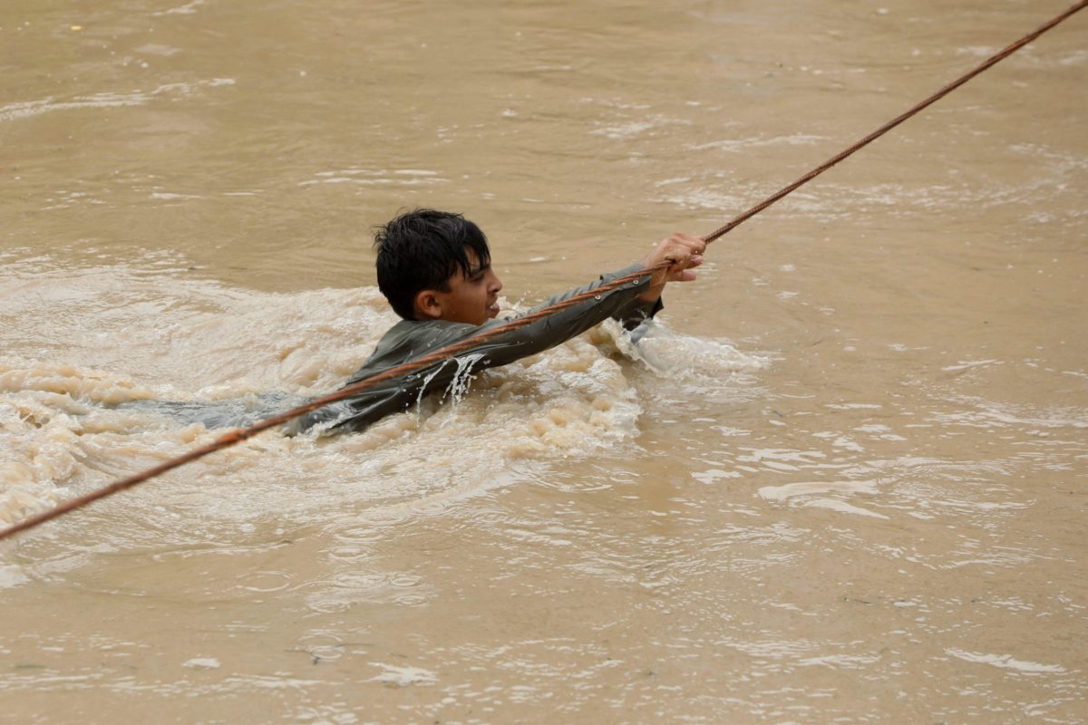 boy hanging on to taut rope in flood
