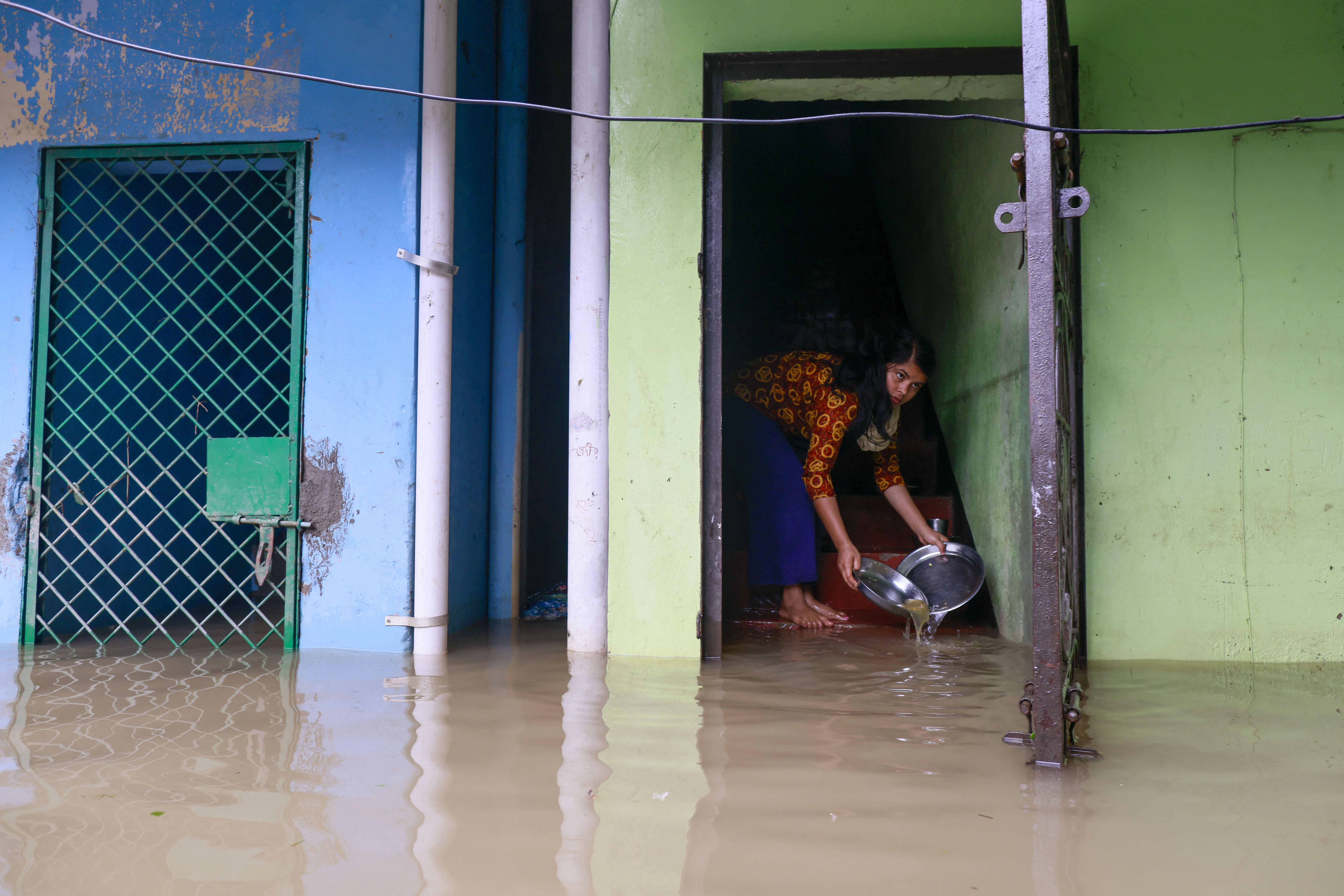A woman bails water from the doorway of a flooded building