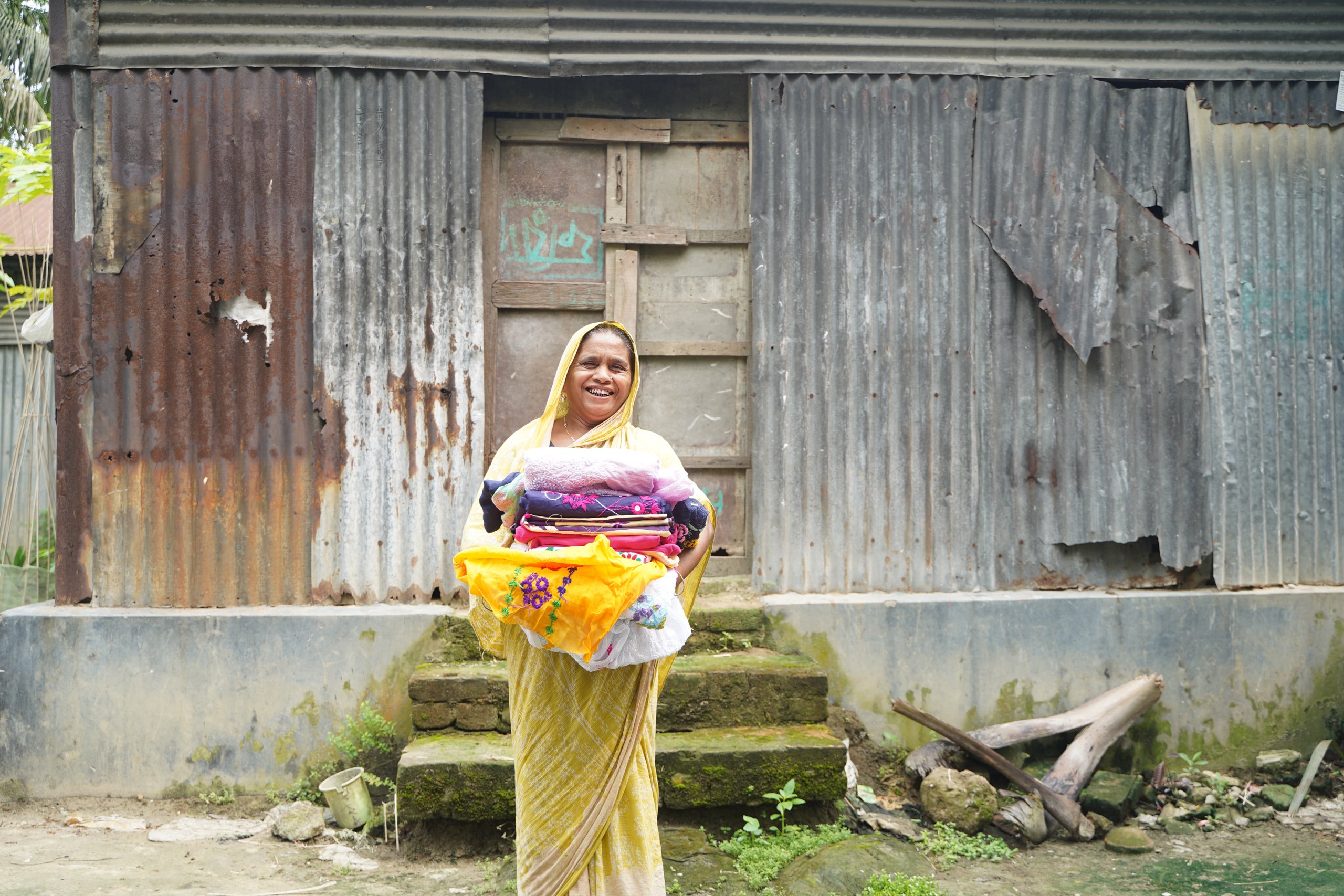 smiling woman carrying bundles of cloth