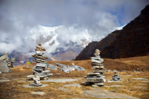 Small piles of stones on ground with cloudy mountain peaks in background