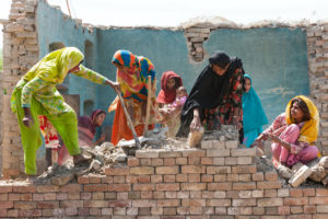 <p>خواتین کا ایک گروپ موزازور، پنجاب، پاکستان میں سیلاب سے تباہ شدہ مکان کی دوبارہ تعمیر کر رہا ہے۔ (تصویر بشکریہ کارو /الامی )</p>