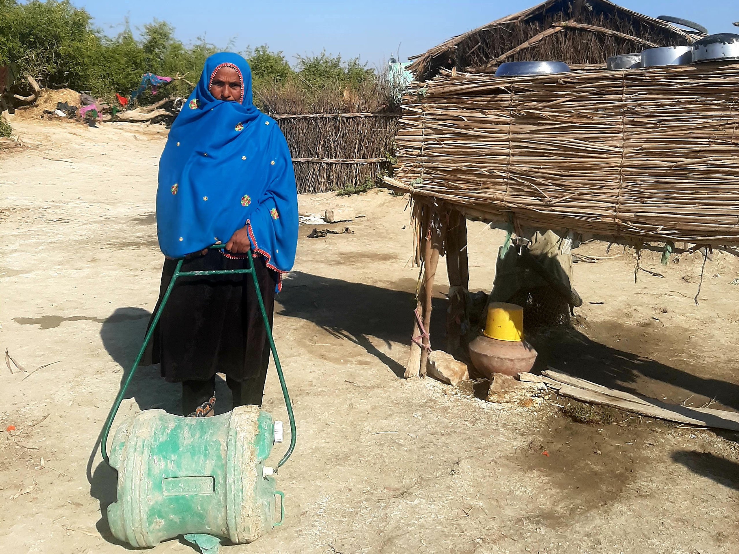 Pakistan woman with a roller water carrier. roller water carrier. In rural Pakistan, women and girls almost always have the job of fetching water for the household
