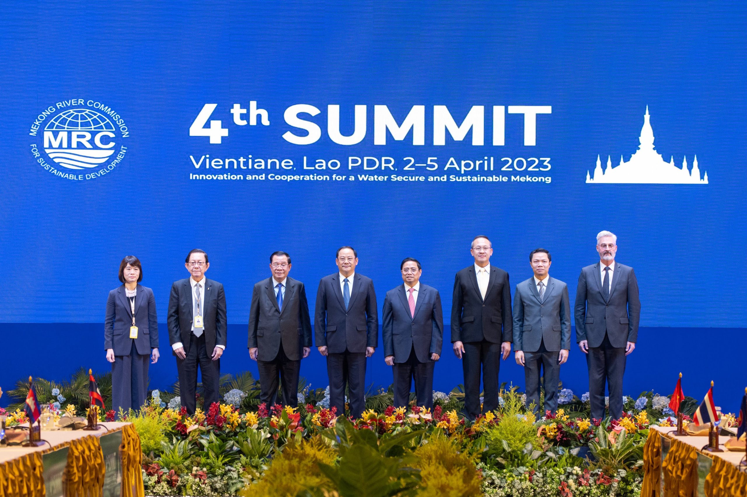 group of people in suits posing in front of Mekong River Commission summit sign