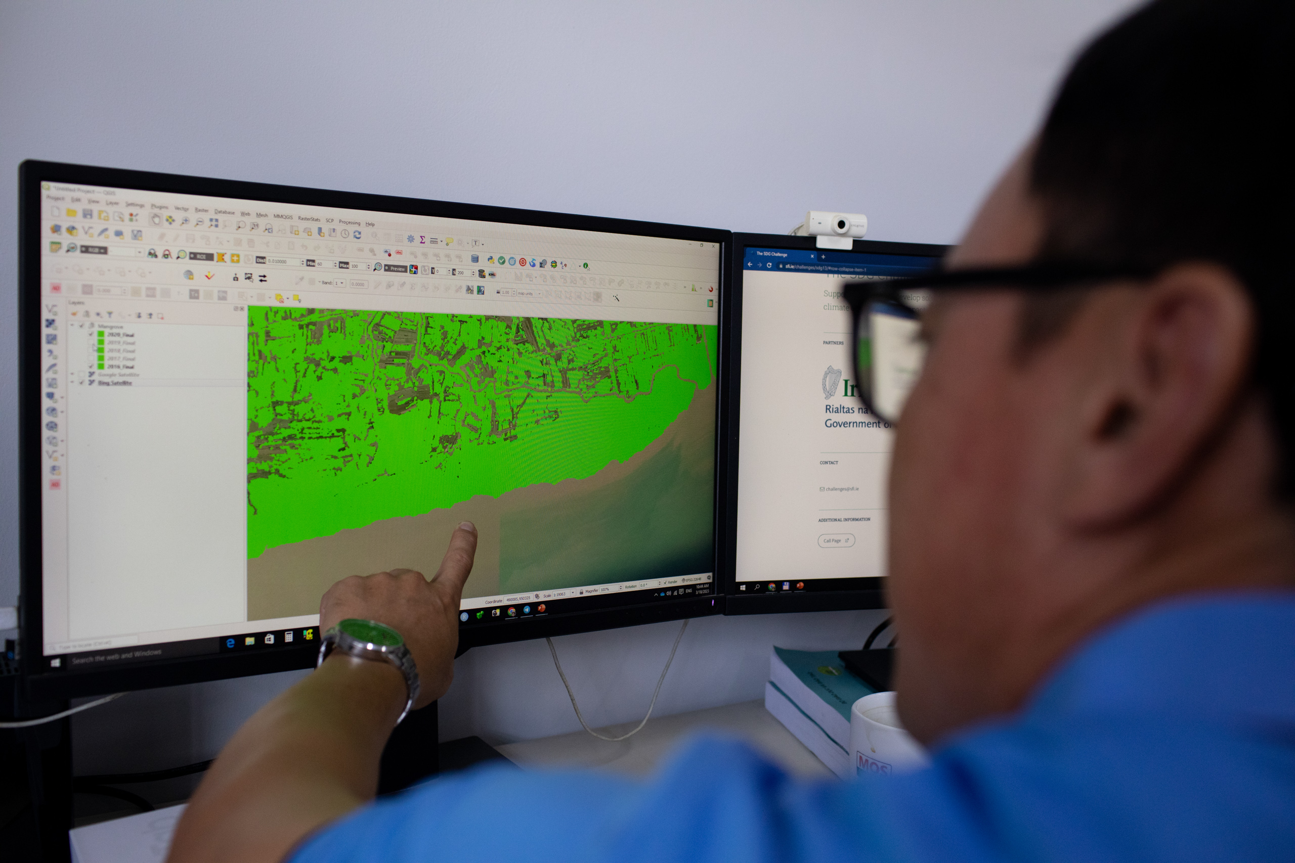 Researcher Vo Quoc Tuan points to a map on a computer screen, explaining what remote sensing data shows about mangrove coverage in the Mekong Delta 