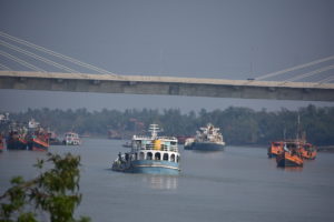Boats transporting cargo along river, passing under bridge, South Asia transboundary rivers