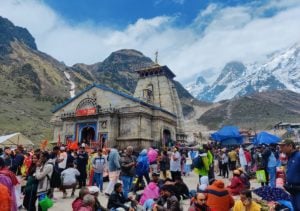 Crowd gathered round a temple, snowy mountains in background