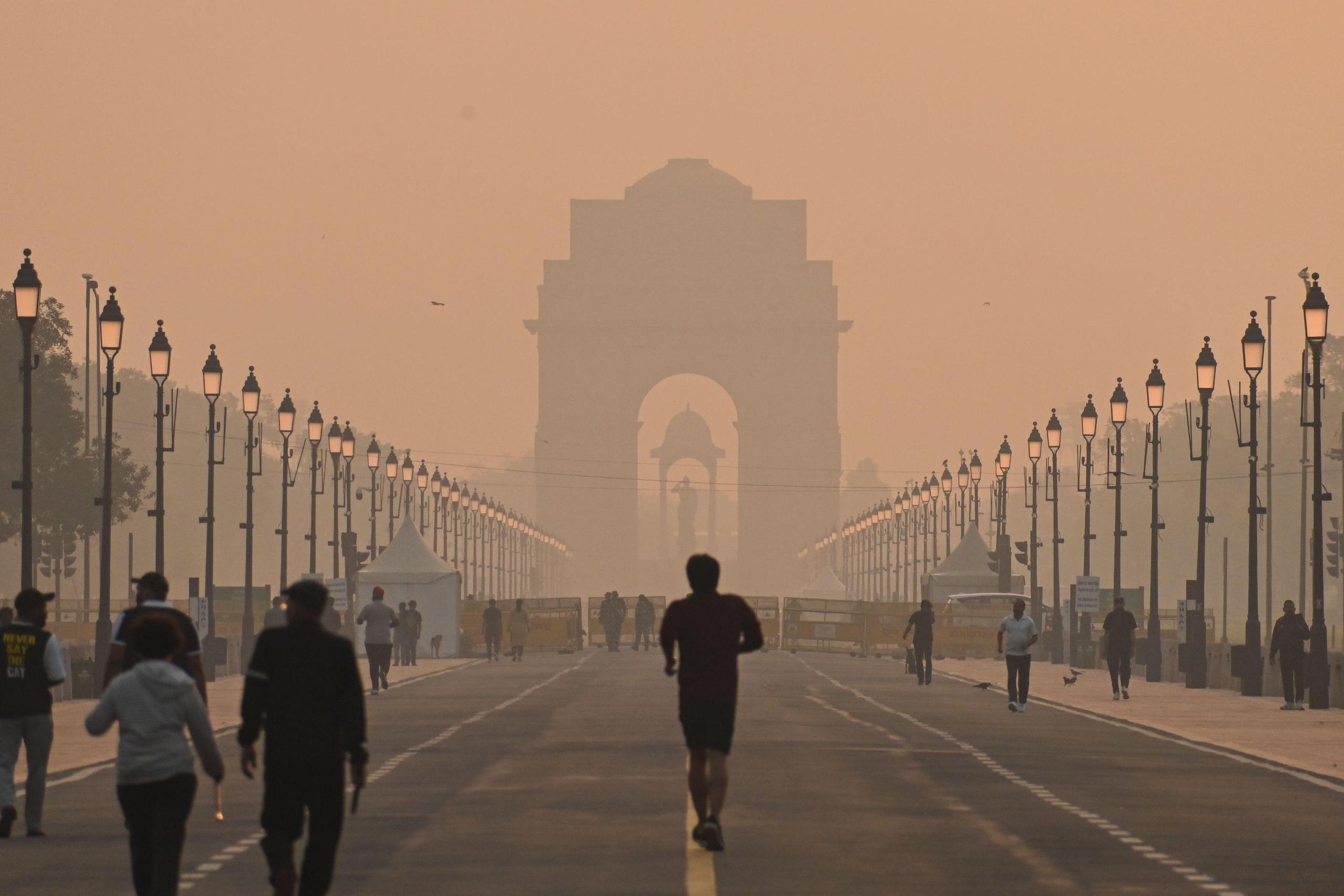 people exercise in yellow smog, with ornate archway in background
