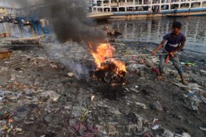 <p>A man burns garbage on the bank of Buriganga River in Dhaka, Bangladesh, on 19 March 2022. Dhaka continues to be ranked as one of the world&#8217;s most polluted cities, with debris from construction, vehicle emissions and brick kilns listed as major contributors to air pollution in the city. (Image: Mamunur Rashid/NurPhoto/Alamy)</p>