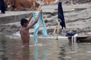 <p>मार्च 2023 में उत्तर प्रदेश के वाराणसी में गंगा नदी में नहाता एक लड़का (फोटो: लूइगी सल्लो / अलामी)</p>