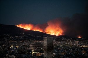 wildfire atop a mountain above city skyline at night