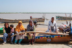 A group of women sat on a boat by a riverbank